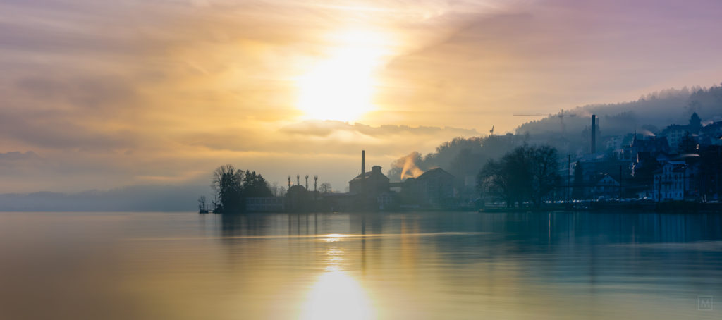 Sun rising and misty skies with historic waterfront buildings on lake Zürich,